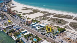 Vista aérea de una ciudad costera con playa, hoteles y puerto deportivo.
