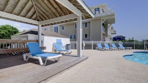 Een overdekt buitengebied met lounge stoelen en een zwembad.