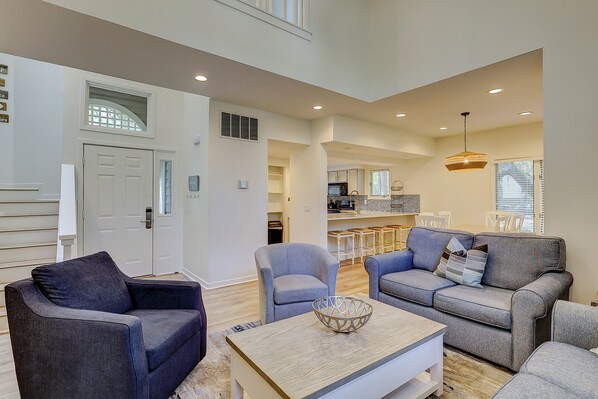 A spacious living area with a sofa set, a coffee table, and a kitchen in the background. - 3 Bedroom/3.5 Bathroom Two-story Villa Near the Ocean with Screened in Porch! (Hilton Head)