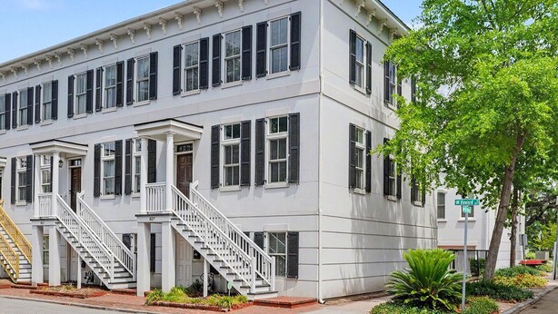 A two-story building with a white facade, multiple windows with shutters, and a central staircase. - Modern Suite for the Traveling Professional by Lucky Savannah (Savannah)