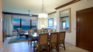 A hotel room with a dining area, a balcony with a view of the sea, and a large mirror on the wall. - Maui Resort Rentals: Marriott's Maui Ocean Club 1BR Oceanfront Villa - New Lahaina and Napili Towers (Lahaina)