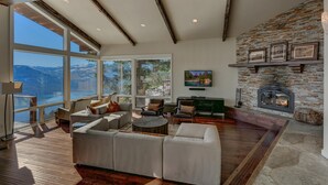 A spacious living room with a large window overlooking a scenic landscape, a fireplace, and a cozy seating area. - Big Sky - Lakeview - TLUXP (Truckee)