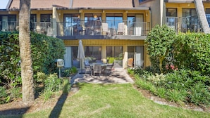 A two-story building with a balcony, outdoor seating, and a well-maintained garden.