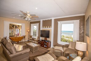 A living room with a sofa, chairs, a coffee table, a TV, and a ceiling fan.