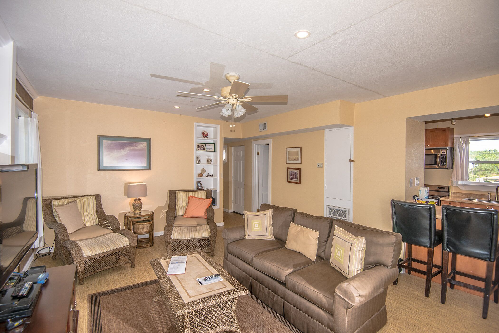 A compact living space with a sofa, chairs, a coffee table, a TV, and a kitchenette.