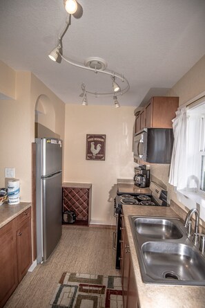 A compact kitchen with a refrigerator, stove, microwave, and double sink. - Idle Hours - Pet Friendly! Gulf Front in Dune Allen Beach (Santa Rosa Beach)