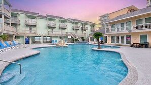 A swimming pool surrounded by multi-story buildings with balconies and outdoor seating areas.