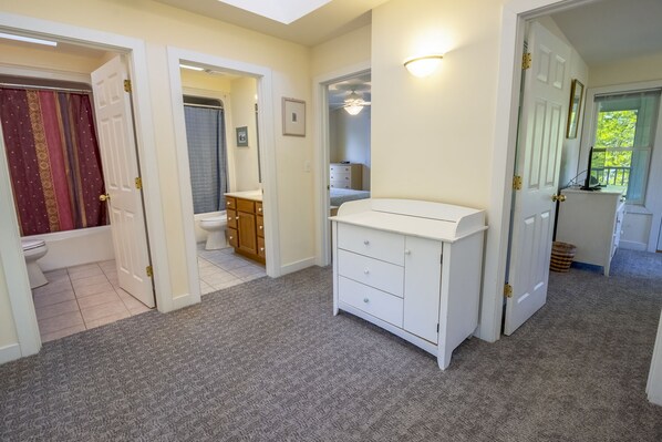 A hallway with a white dresser, a bathroom with a toilet and sink, and a bedroom with a bed and dresser. - 5 Beds in Beachwalk Resort - Beach, Pool, Stocked Lake & Lake Michigan Access (Michigan City)