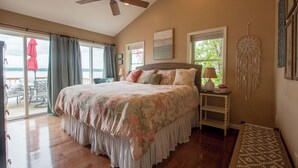 Un dormitorio con una cama grande, un ventilador de techo, vistas al exterior y un atrapasueños en la pared.