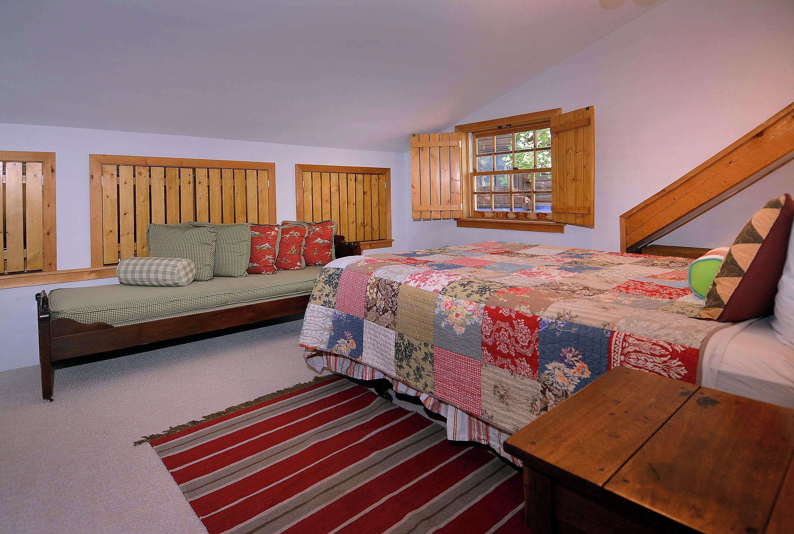 A bedroom with a bed, a window, a wooden headboard, and a small table.