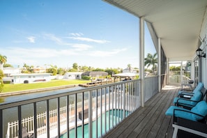 Ein überdachter Außenbereich mit Pool, Liegestühlen und Blick auf eine Wohngegend.