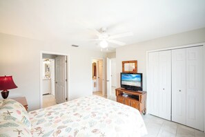 Ein Schlafzimmer mit einem Bett, einem Fernseher auf einem Holzboden, einem Deckenventilator und einem Kleiderschrank.