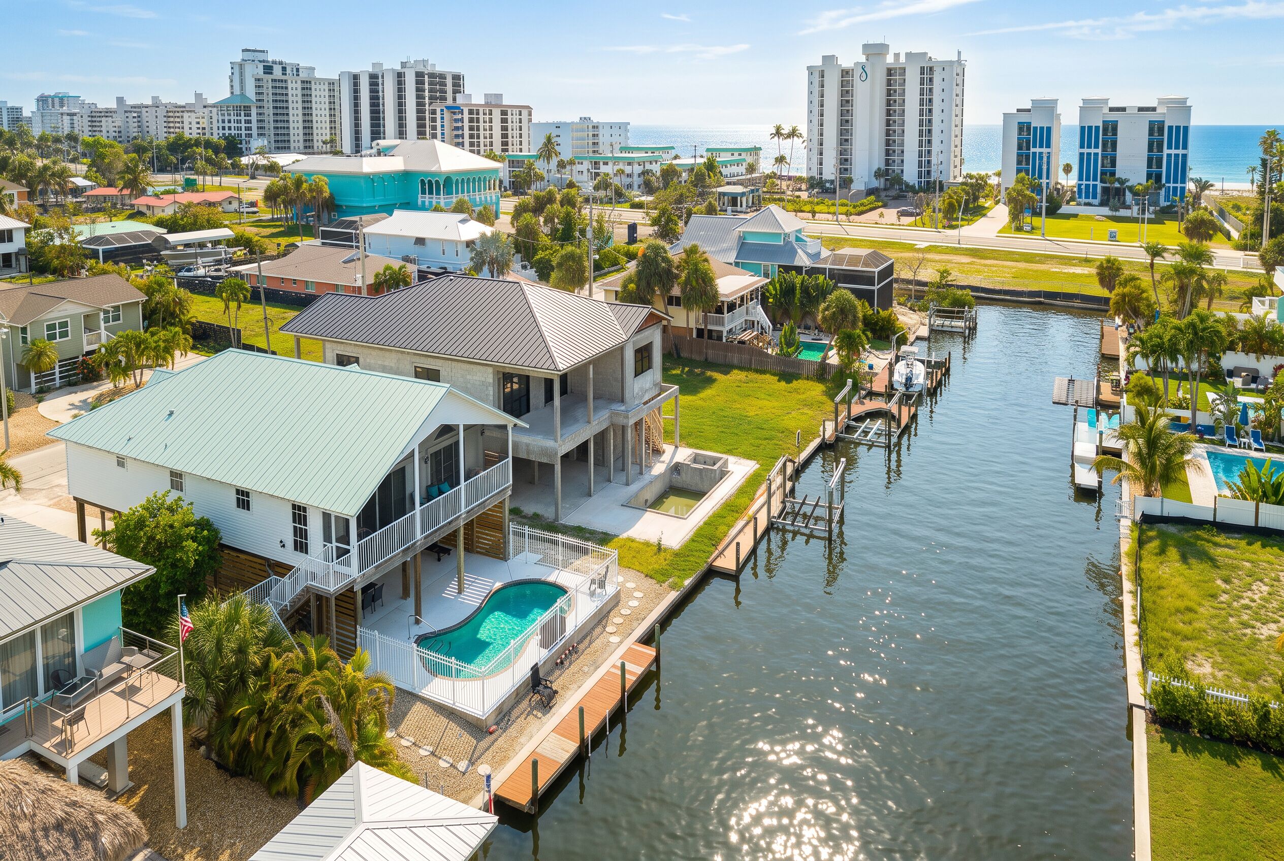 A residential area with a canal, houses, and a view of the ocean.
