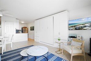 A modern kitchen with white cabinets, a dining area with a round table, and a large wardrobe. - "Inlet Sands 204" | 1 min. walk to beach | Community Pool | Bike to Rosemary (Inlet Beach)