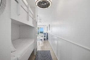 Ein schmaler Flur mit einem Etagenbett, einem Deckenventilator und Blick ins Freie.