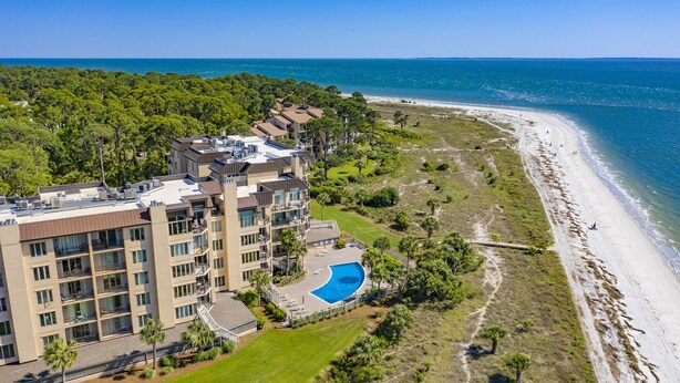 Un hôtel à plusieurs étages doté d’une piscine sur le toit, d’un accès direct à la plage et d’une végétation luxuriante.