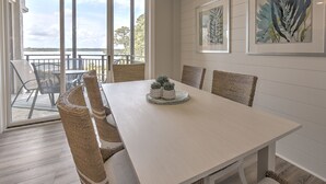 Un coin repas avec une table blanche, des chaises en osier et une petite plante servant de décoration centrale.