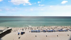 A beach with umbrellas and a building in the background.