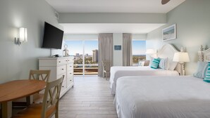 Ein Hotelzimmer mit Balkon, Fernseher, Schreibtisch und zwei Betten.