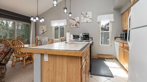 A modern kitchen with a central island, wooden cabinets, and pendant lighting.