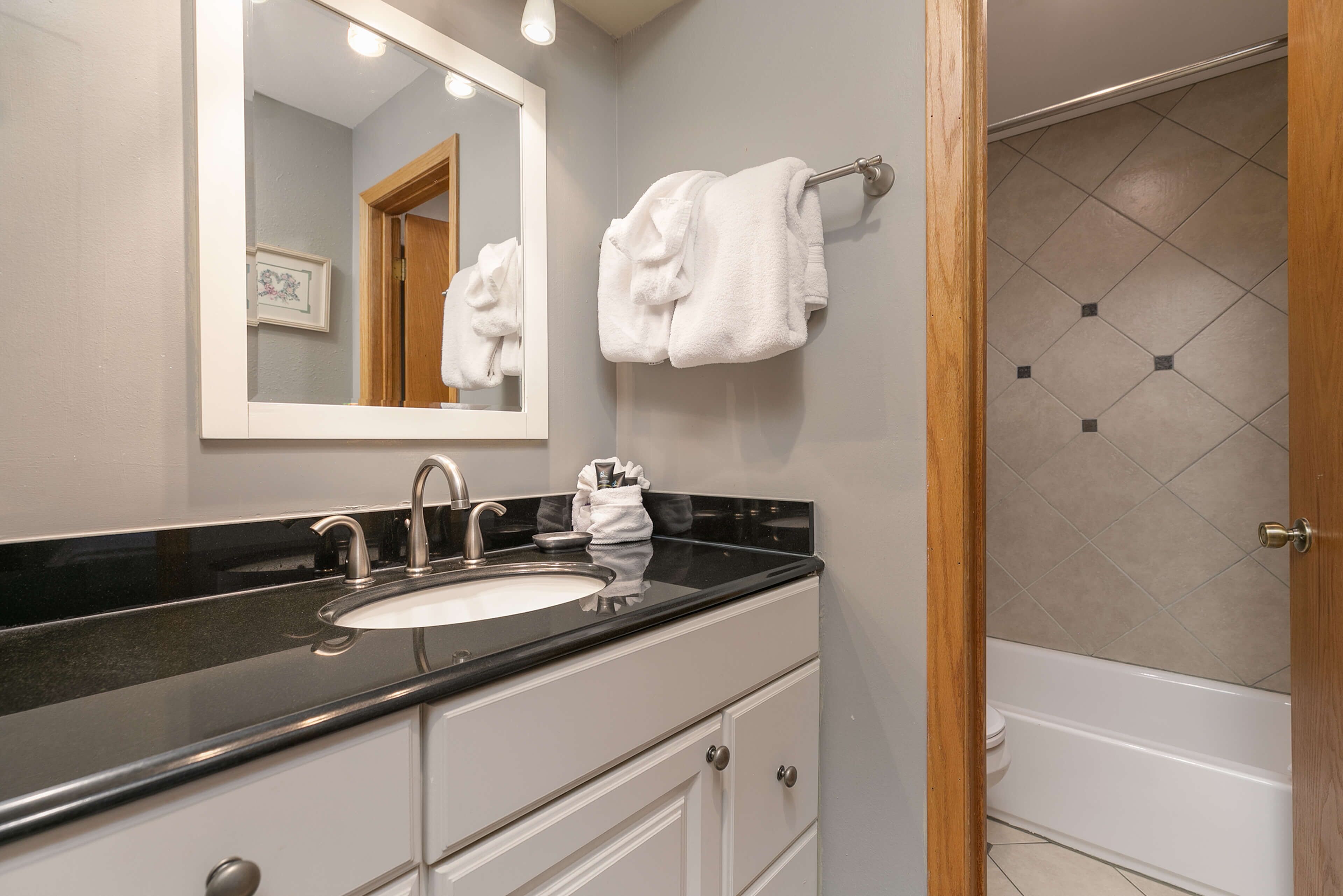 A bathroom with a double sink, a mirror, and a towel rack.