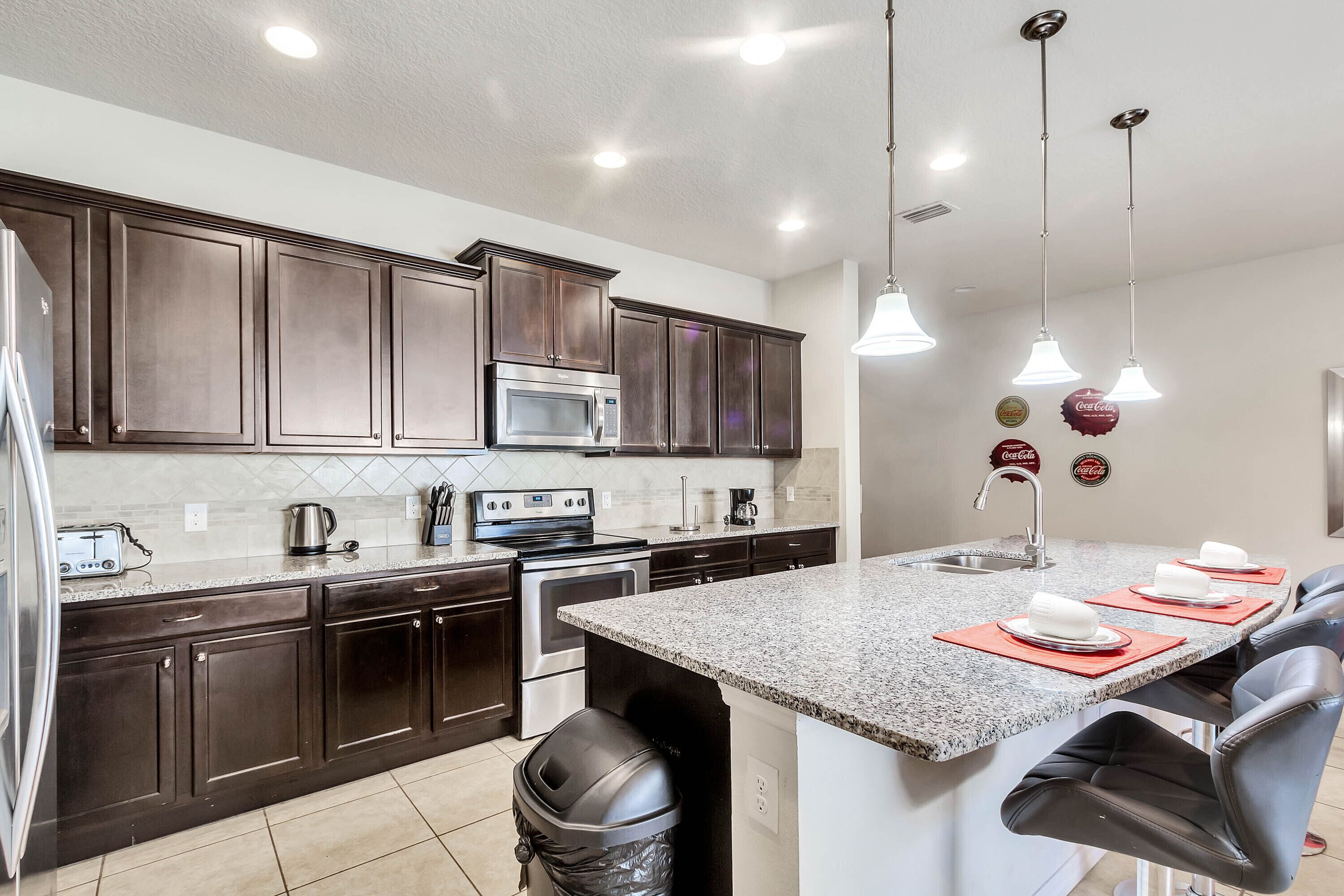 A modern kitchen with dark wood cabinets, stainless steel appliances, and a granite countertop.