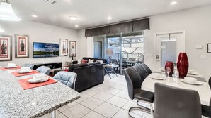 A modern kitchen with a dining area, granite countertops, and a large window. - EV_1957 - 4BR / 3BA Villa w/ Private Pool & Spa, Themed Kids' Rooms & Resort (Kissimmee)