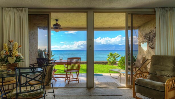 Ein Zimmer mit einer Schiebetür und einem Balkon mit Blick auf das Meer und ein Gebirge.