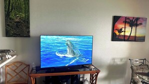 Ein Fernseher zeigt einen Wal, ein Holzstuhl und eine Wand mit zwei Bildern.