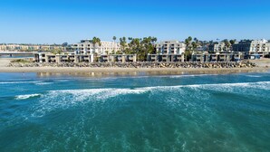 Ein Strandhotel mit mehreren Gebäuden, einer felsigen Küstenlinie und klarem, blauem Wasser.
