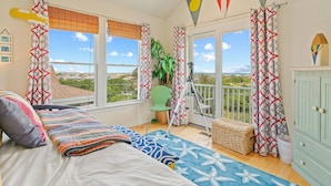 Une chambre avec un lit, une chaise, un trépied et une vue sur l’extérieur.