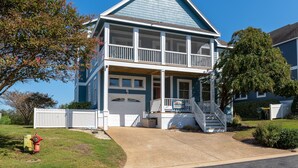 Une maison à deux étages avec un porche à l’avant, un garage et un escalier menant au deuxième étage.