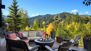 Une terrasse avec mobilier d’extérieur, un foyer et une vue panoramique sur les montagnes.