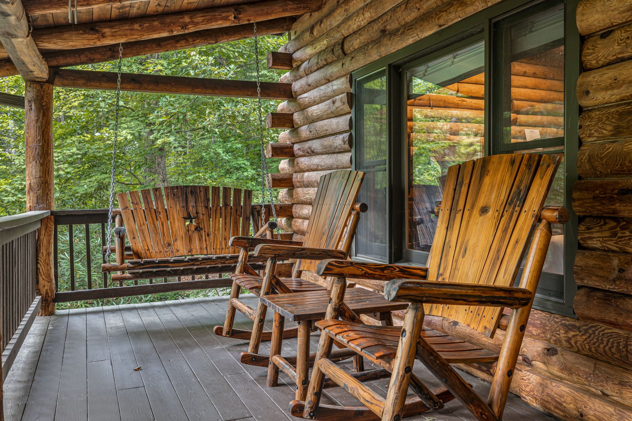 A wooden porch with several rocking chairs and a wooden deck.