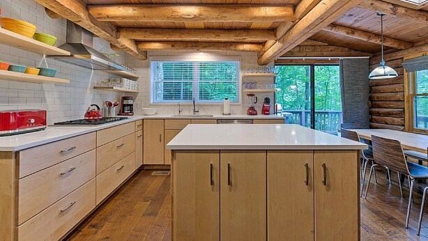 A modern kitchen with wooden beams, white countertops, and a large island.