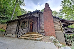 Une cabane rustique avec une façade en pierre, une cheminée en briques et une terrasse en bois.
