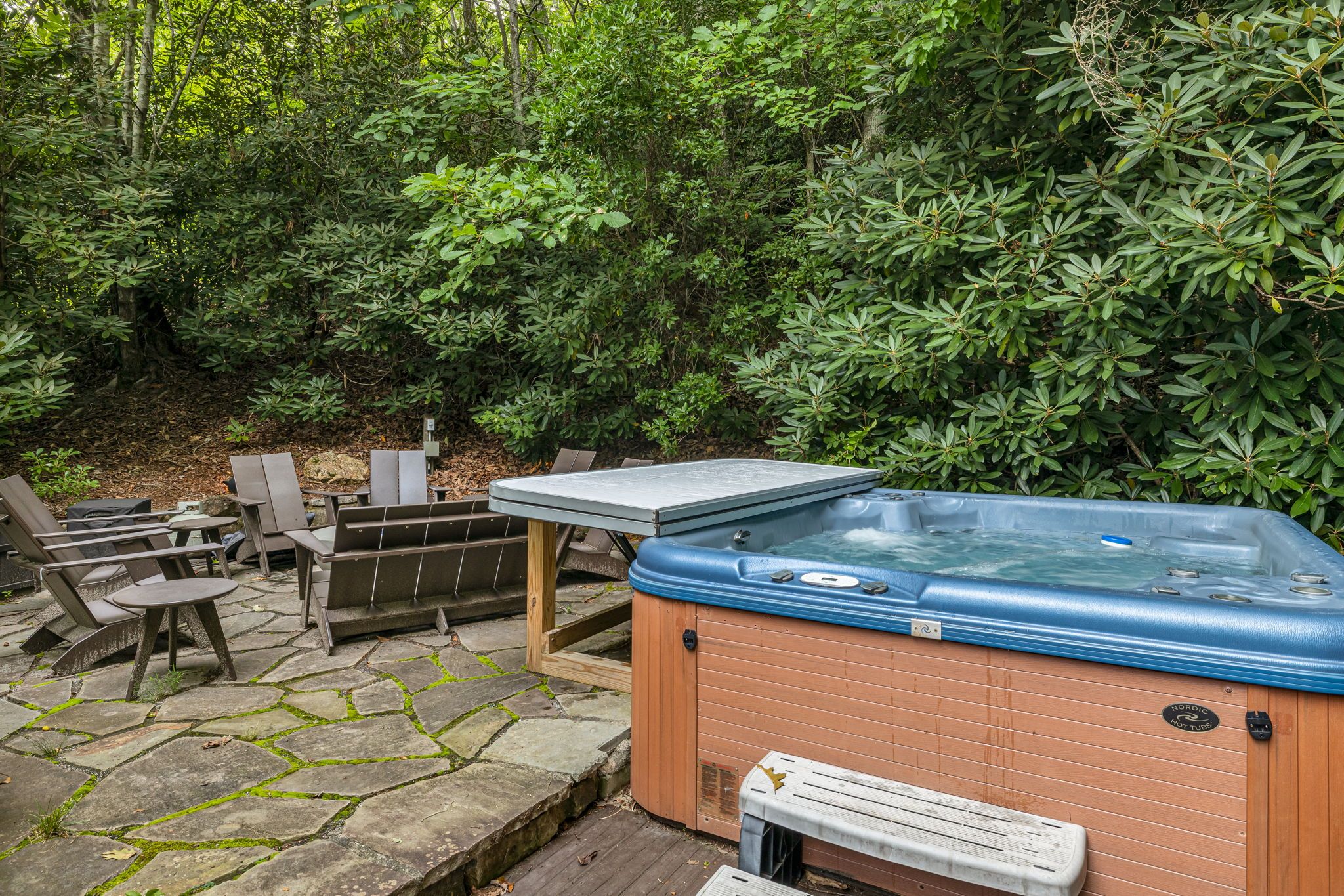 An outdoor hot tub area with seating and a stone patio.