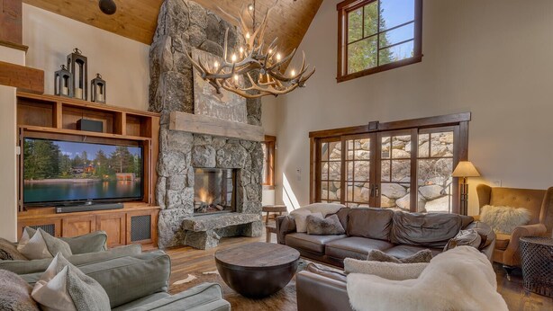 A cozy living room with a stone fireplace, leather sofas, and a large flat-screen TV.