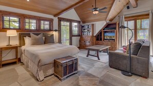 A bedroom with a bed, bedside tables, a wooden chest, a sofa, a TV, and a ceiling fan.