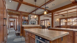 A spacious kitchen with wooden cabinets, a stone island, and a stone fireplace.