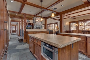 A spacious kitchen with wooden cabinets, a stone island, and a stone fireplace.