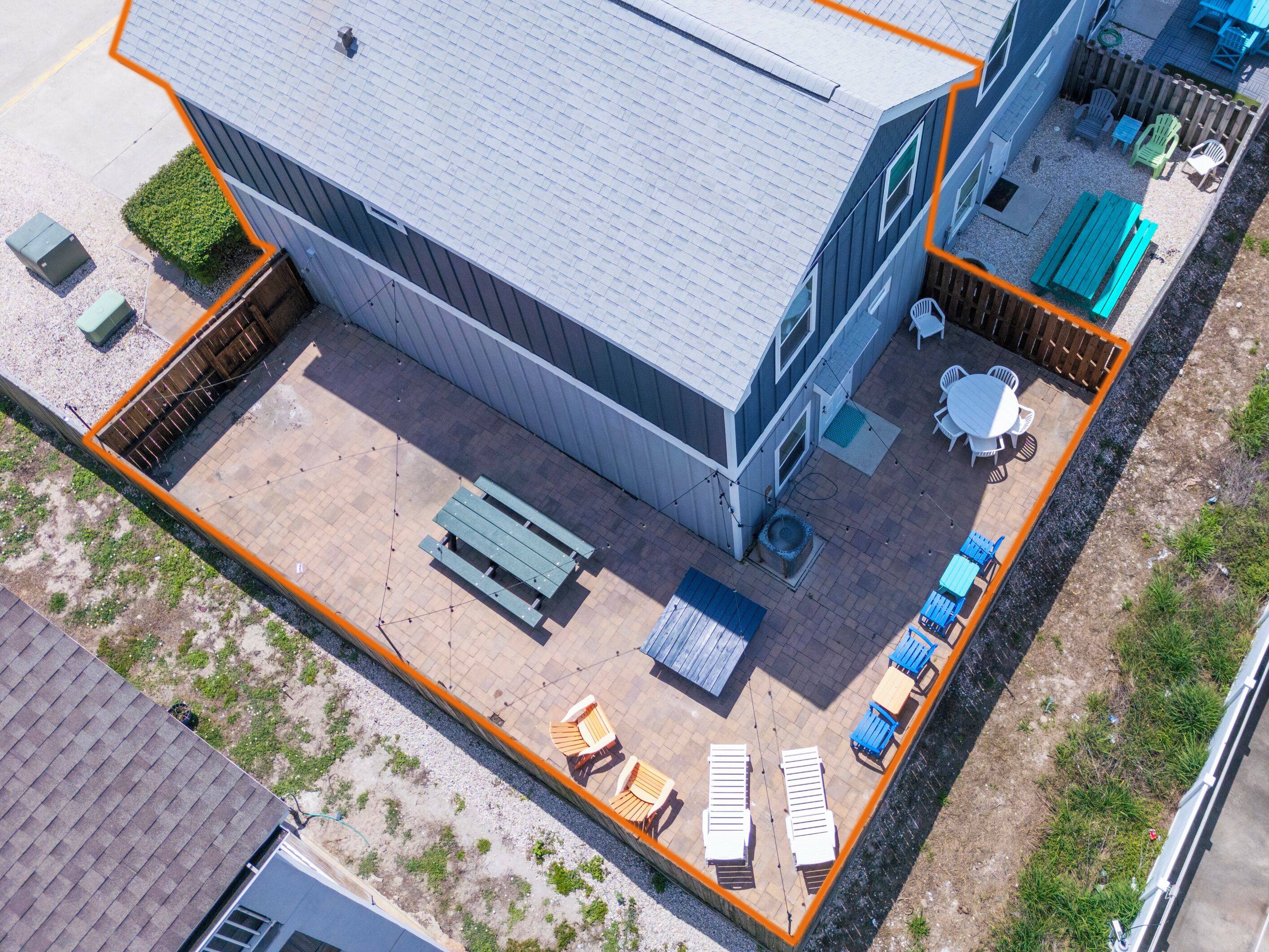 An aerial view of a building with a fenced patio area containing outdoor seating and a small garden.