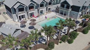 Un hôtel à plusieurs étages doté d’une piscine, d’un espace extérieur aménagé et de palmiers.