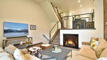 A living room with a fireplace, a television, and a staircase leading to an upper level.