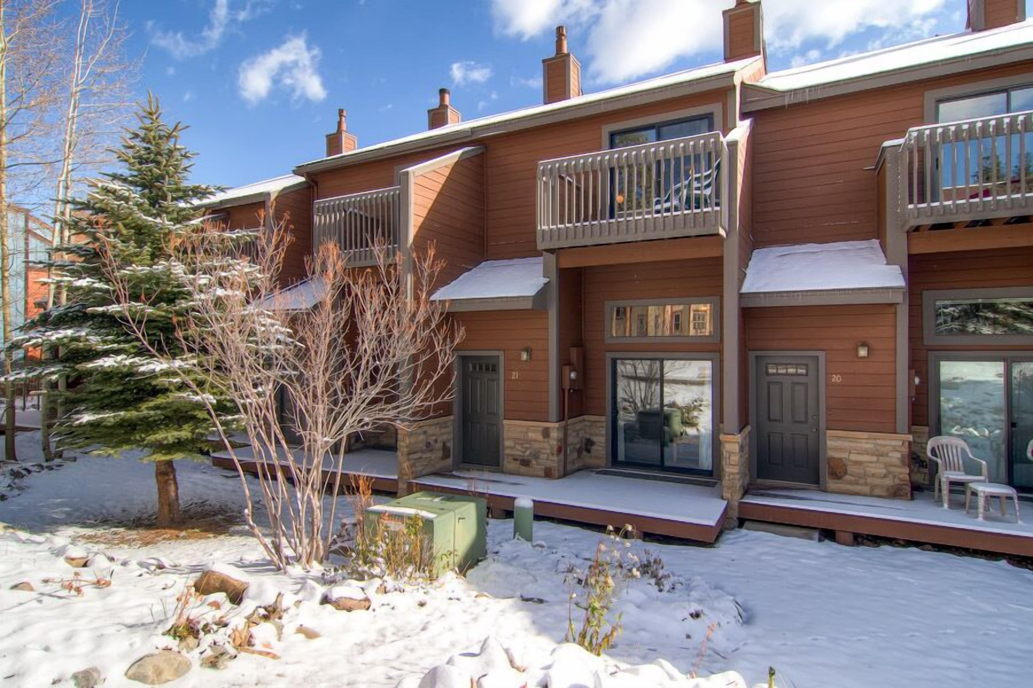 A multi-story building with a wooden facade, balconies, and a snow-covered ground.