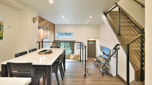 Un interior moderno con comedor, escalera y vistas al exterior.