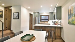 Una cocina moderna con una isla central, electrodomésticos de acero inoxidable y un comedor con mesa y sillas blancas.
