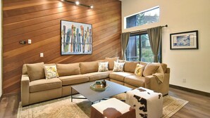 Una sala moderna con un sofá modular, una mesa de centro y un otomano de cuero de vaca.