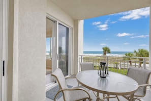 A balcony with a glass door, a round table, and four chairs. - 3204 SeaCrest - Direct Oceanfront -March/April Heated Pool (Hilton Head Island)