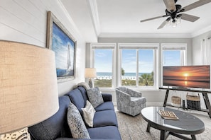 A living room with a sofa, armchair, TV, and a ceiling fan. - 3204 SeaCrest - Direct Oceanfront -March/April Heated Pool (Hilton Head Island)